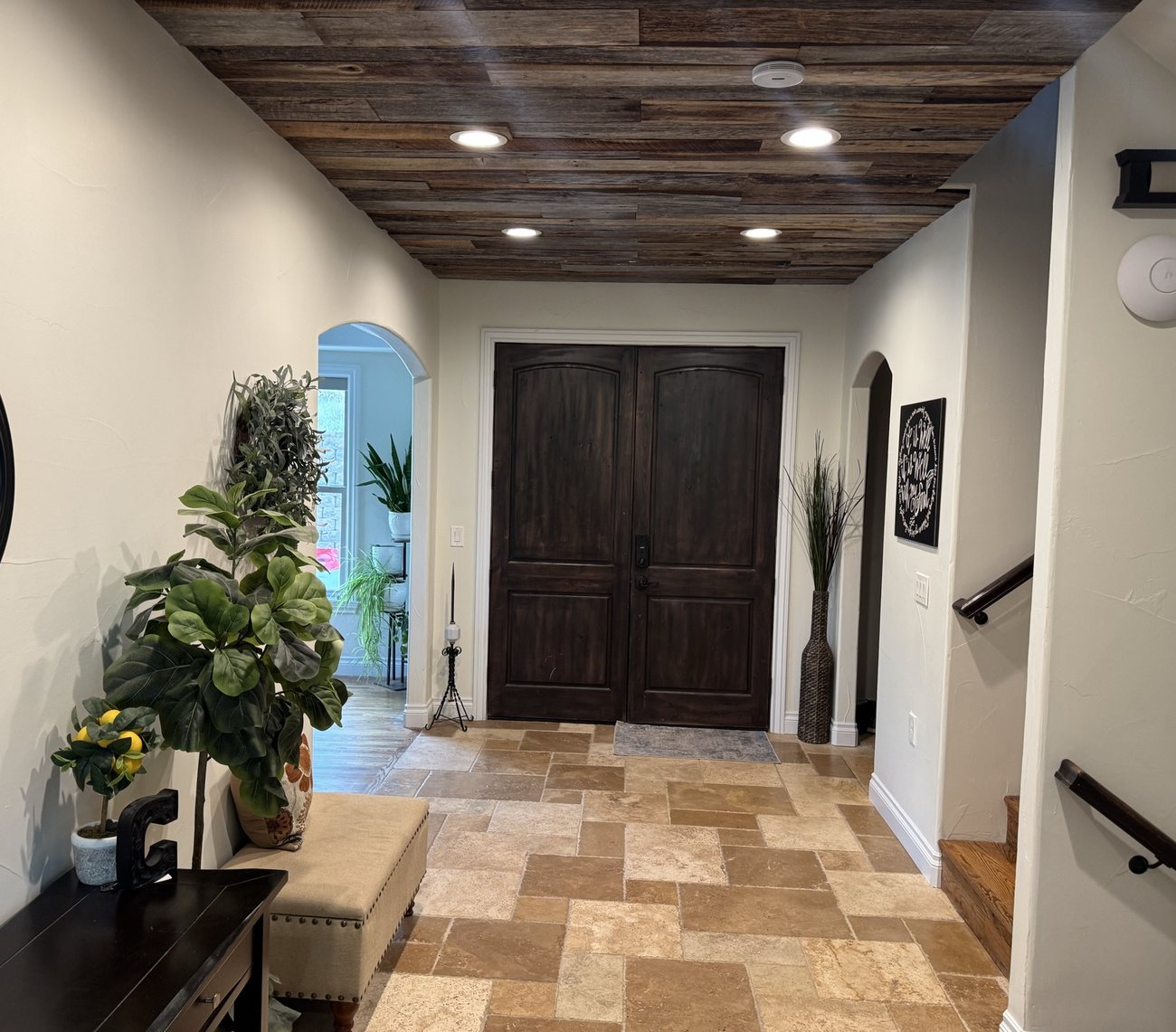 Entry hall with a stained wood plank ceiling above travertine flooring