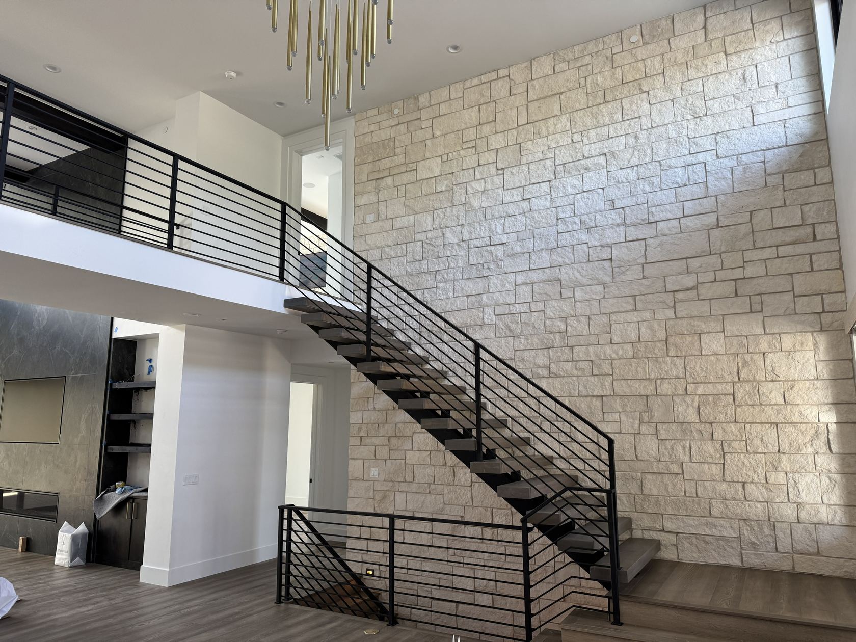 Floating staircase against a two-story stone wall