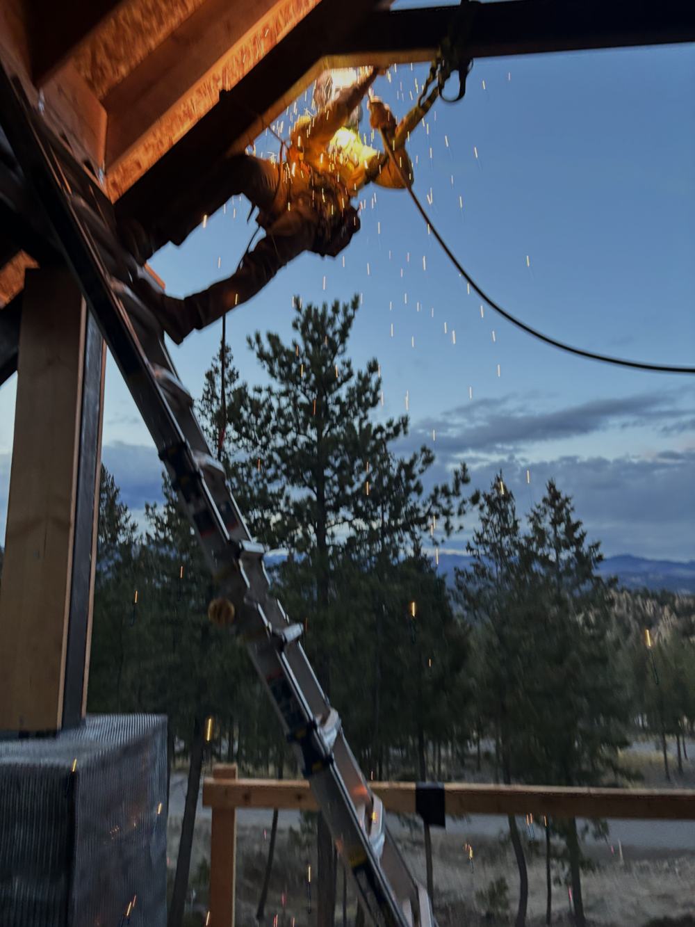 Craftsman welding structural steel at dusk