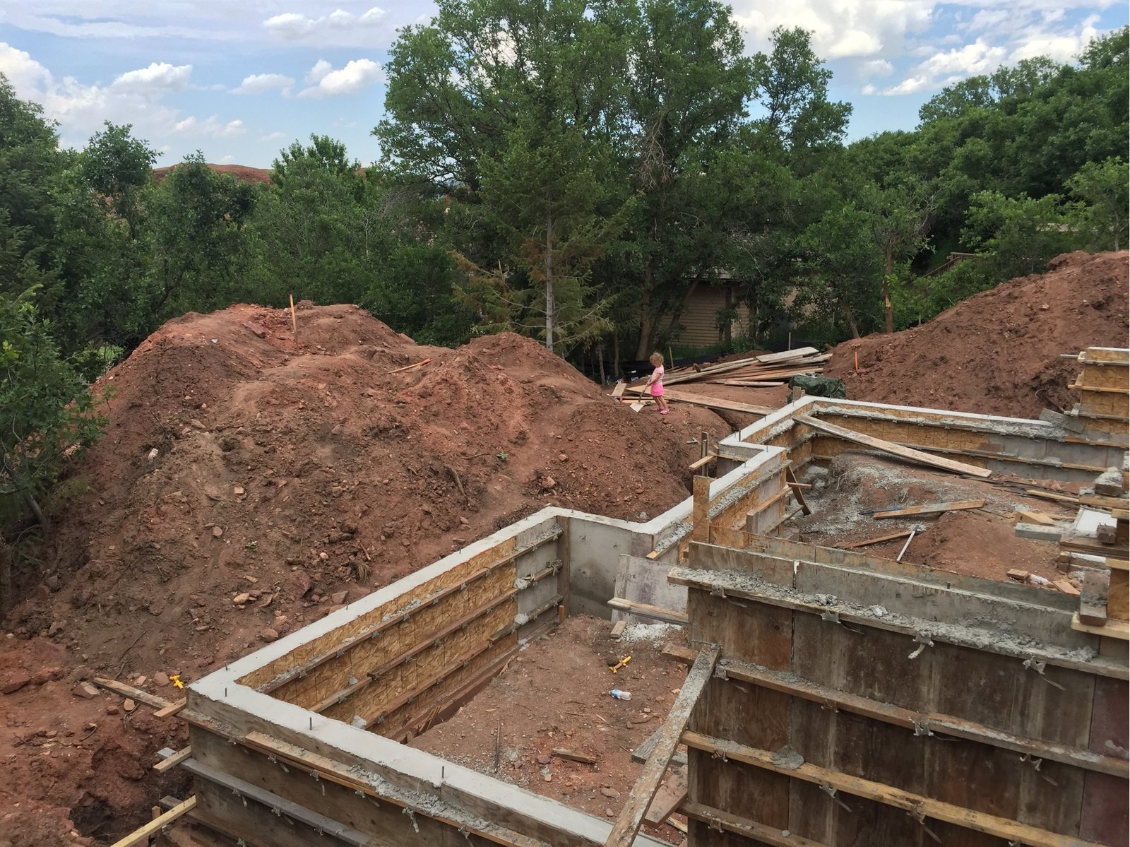 Foundation wall forms set and braced, excavated spoils piled behind