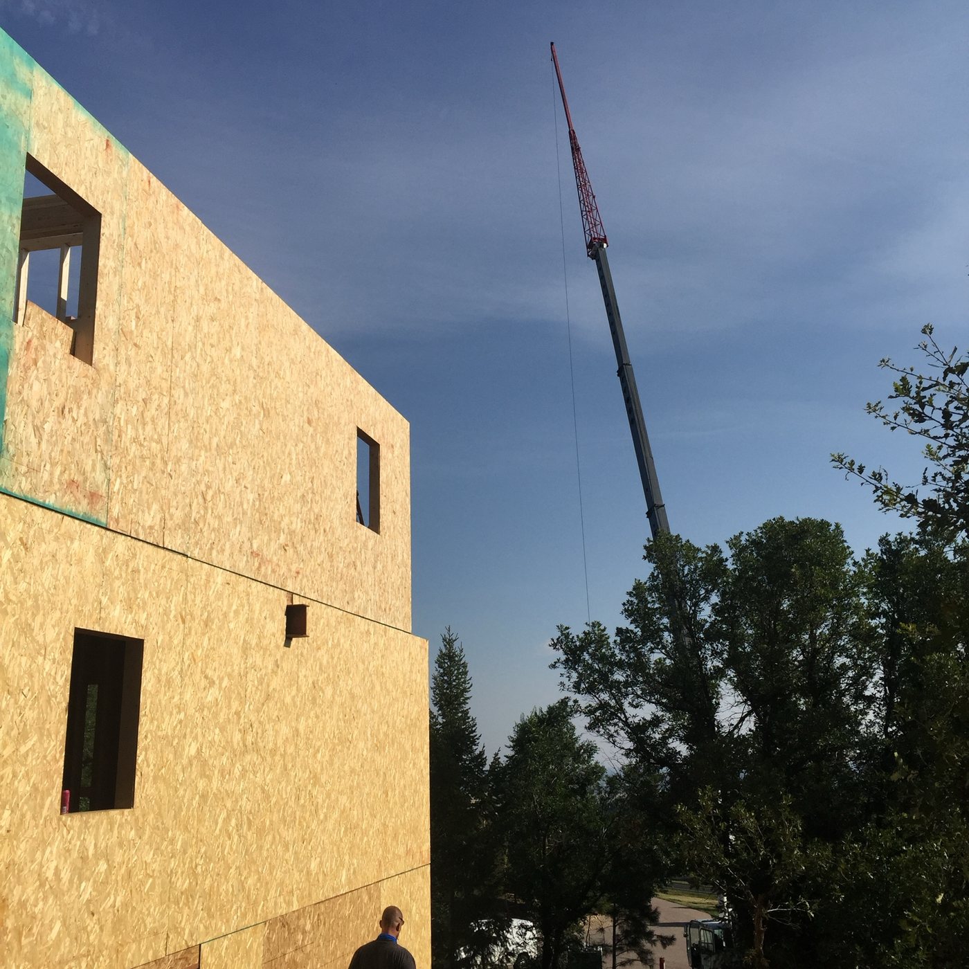 Sheathed exterior wall standing with a crane boom rising behind it
