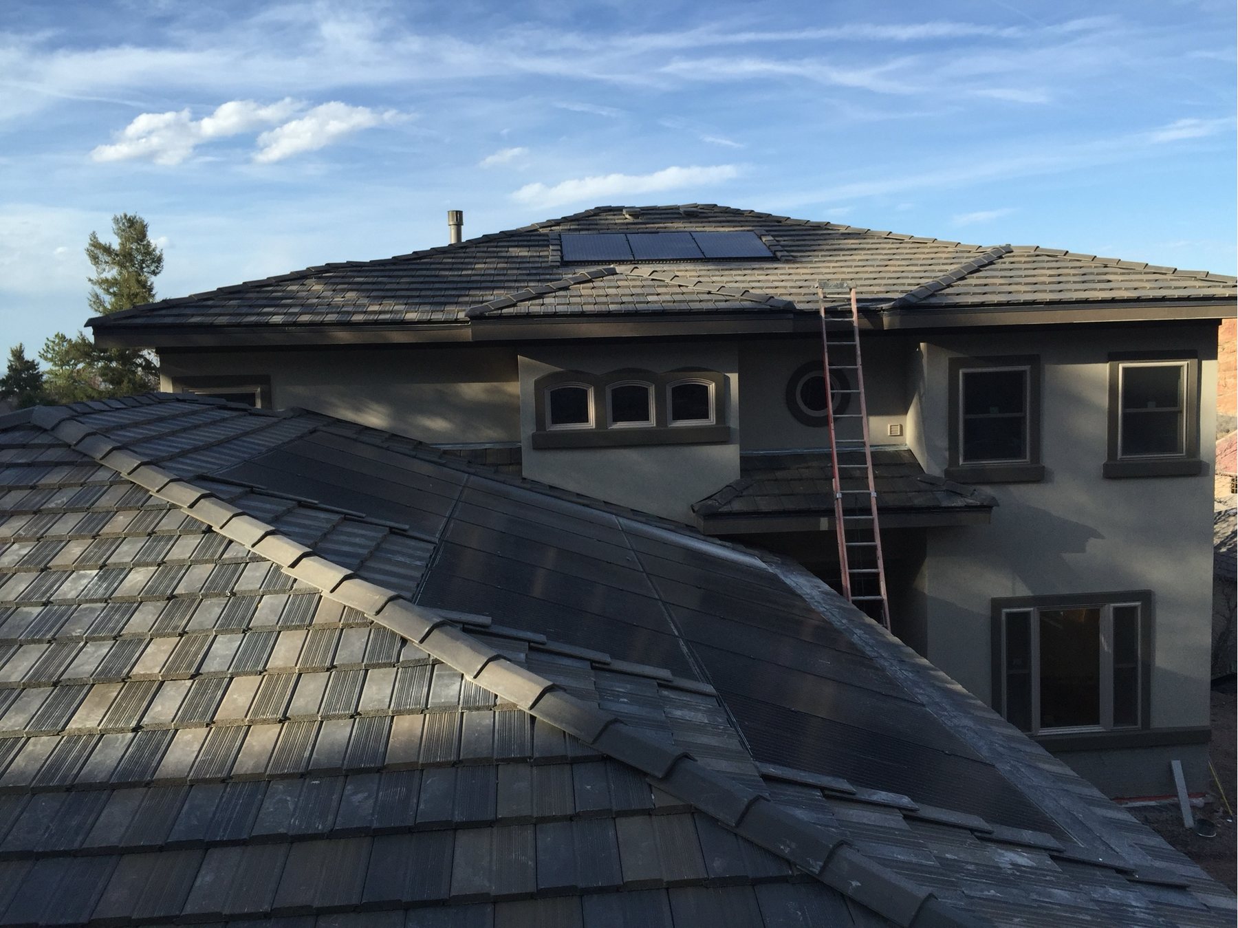 Concrete tile roof and stucco elevation against a Colorado sky.