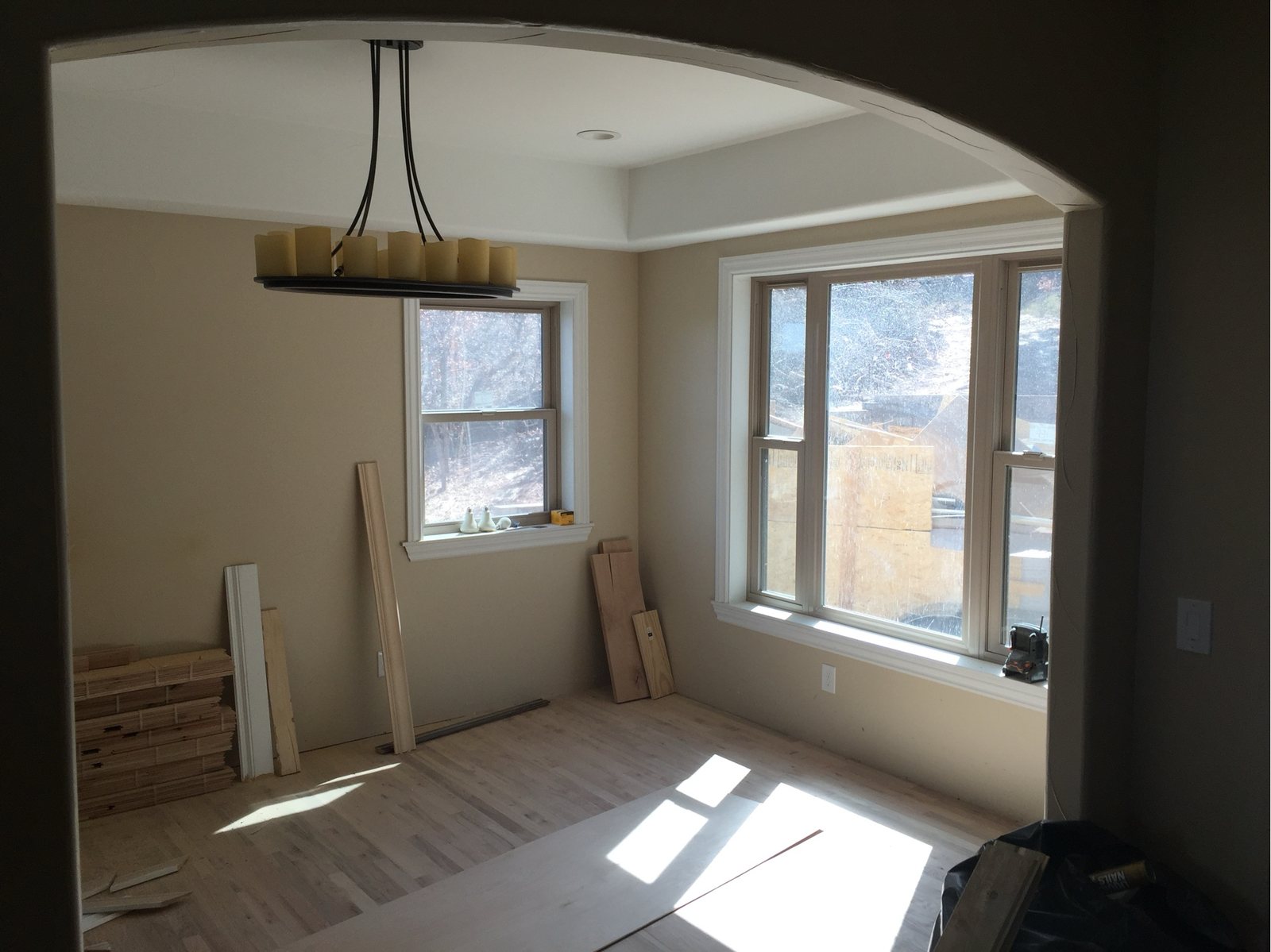 Interior arched openings and a window bay at the drywall stage, light falling across the floor
